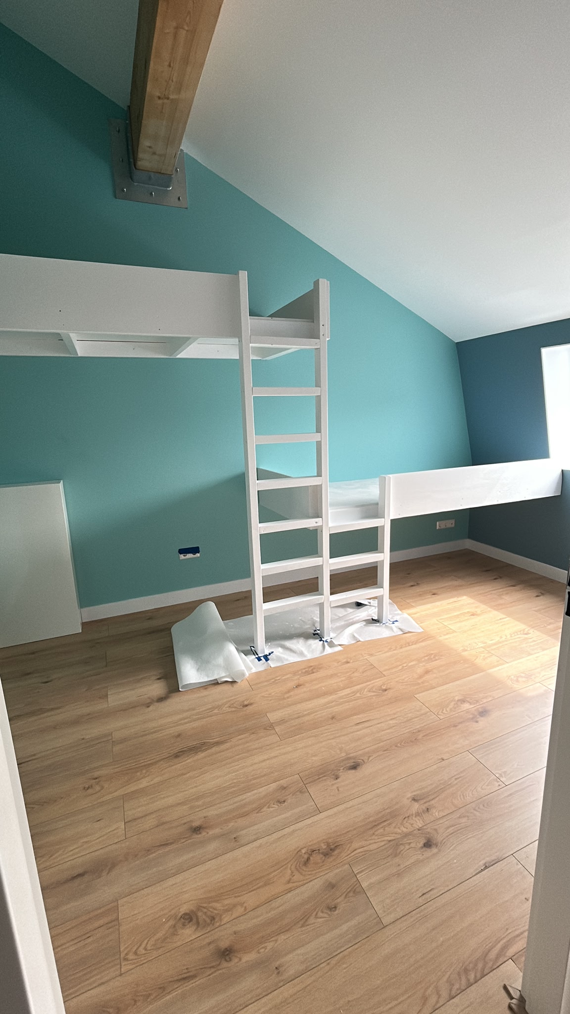 Interieurkamer met turquoise schilderwerk en houten vloer