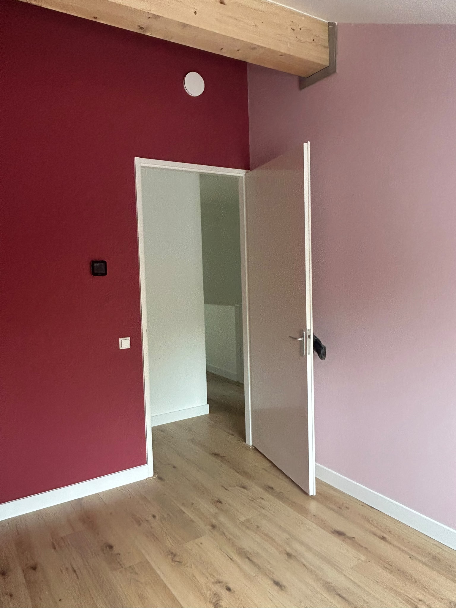 Interieur met rode accentwand en zachte roze wandkleur
