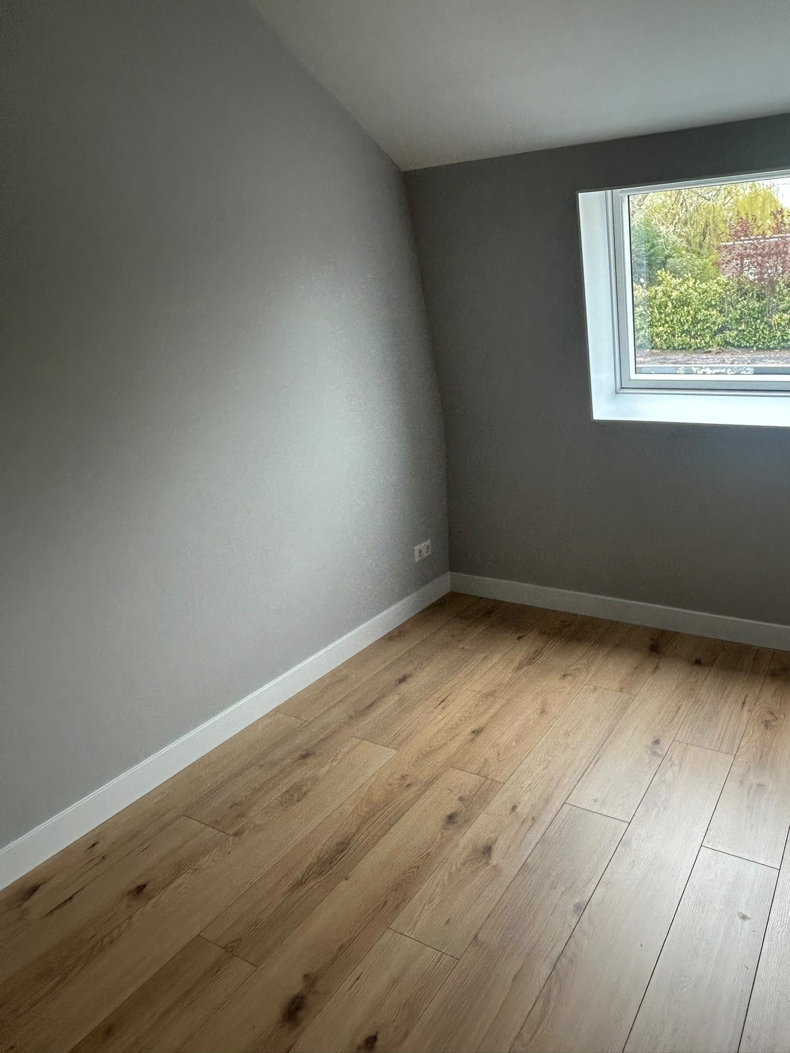 Kamer met grijze wandafwerking en raamlicht