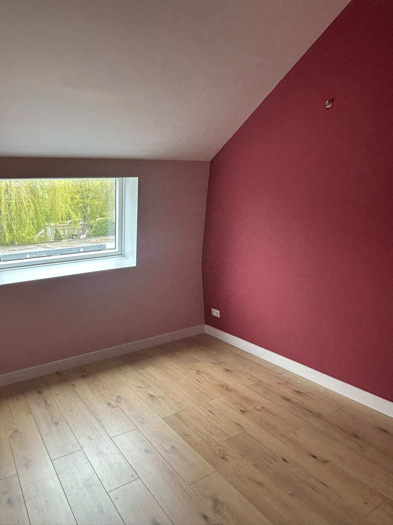 Kamer met rood kleurvlak onder schuin plafond