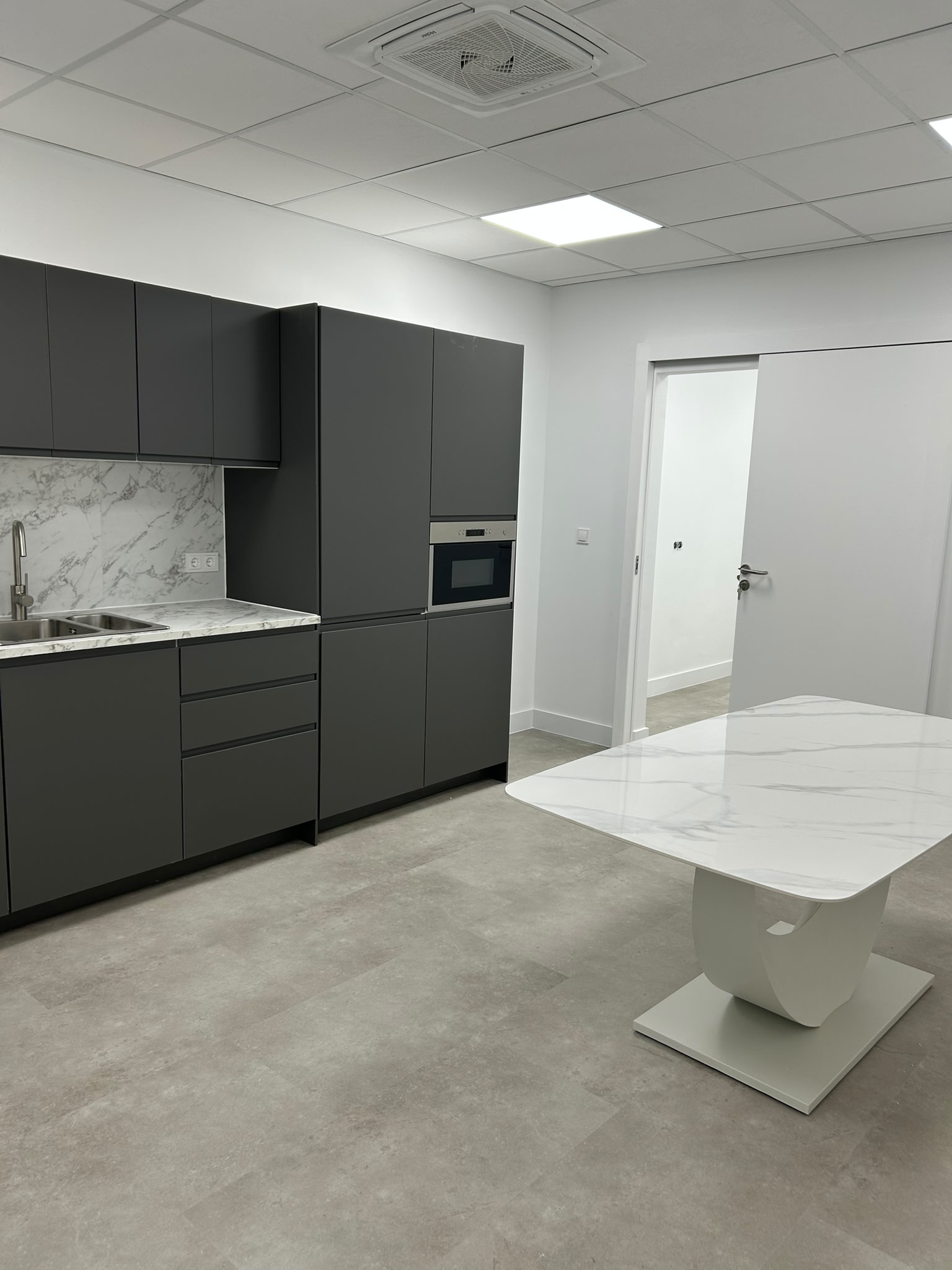 Keuken met donkergrijze kasten en strak plafond met lichtpanelen